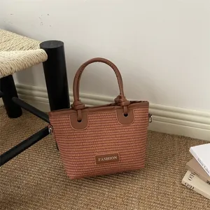 Stylish straw woven bucket bag with leather handles and chic knot design, perfect for beach.