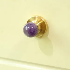 Close-up of a luxury natural amethyst cabinet knob with a gold base, perfect for furniture.