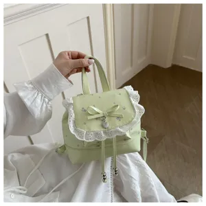 Primo piano di un mini zaino verde chiaro dolce con delicato bordo in pizzo e stampa floreale.