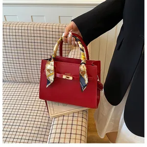 Red women handbag detail showing leather texture, metal lock, and chic silk scarf handle wrap.