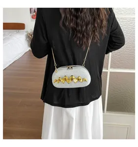 Nahaufnahme der silbernen glitzernden Umhängetasche mit elegantem goldenen Wellendekor.
