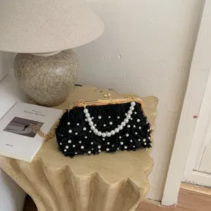 Élégante sacoche de soirée noire en résille florale avec poignée perle et chaîne dorée.