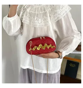 Nahaufnahme einer roten glitzernden Schultertasche mit auffälligem goldenem Wellendesign.