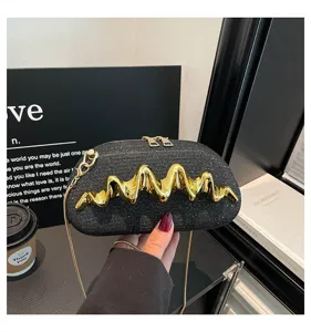 Detailansicht der schwarzen Glitzer-Umhängetasche mit goldener Wellen-Metalldekoration.