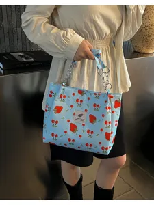 Blue strawberry print tote bag detail showing cute pattern, fabric texture and chain strap.