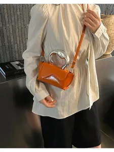 Nahaufnahme der trendigen orangen Lacktasche mit einem einzigartigen Metallgriff.