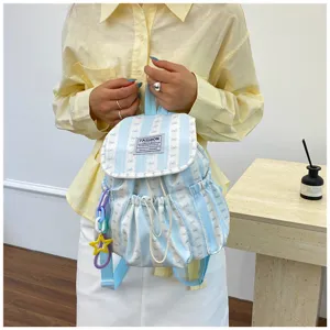 Close-up detail of the light blue striped backpack with front bow pattern and cute charms.
