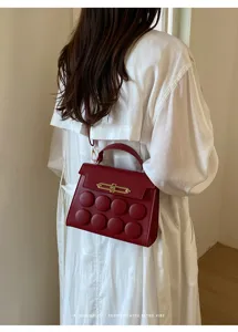 Women dark red shoulder handbag with unique round button design and gold hardware stylish