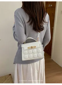 Close-up detail shot of the white leather shoulder bag with unique puffy circle embossed decor.
