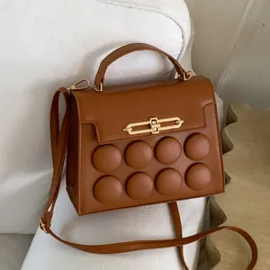 Stylish brown leather shoulder bag with chic metal lock and unique circular padded front design.