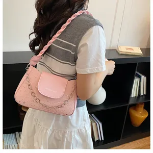 Vue de detail du sac rose avec bandouliere tressee et decoration de chaine elegante.