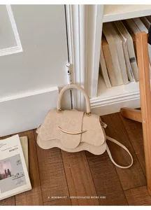 Detalle de bolso de ante beige chic, elegante cierre metálico curvo y diseño minimalista.