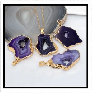 Gedetailleerd uitzicht van natuurlijke paarse agaat geode hanger met vergulde rand, ruwe steen.