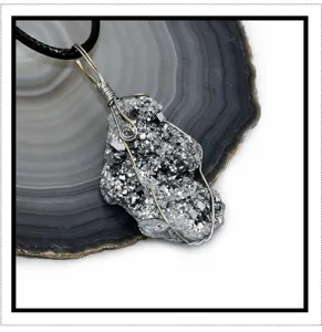 Raw druzy crystal cluster pendant detail shot, wire wrapped irregular gemstone necklace accessory.