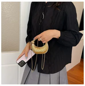 Detailed shot of sparkling gold metal ring handle mini evening bag with fine chain strap.