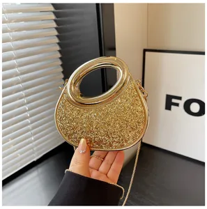 Close-up detail of sparkling gold evening bag featuring chic oval handle and glitter texture.
