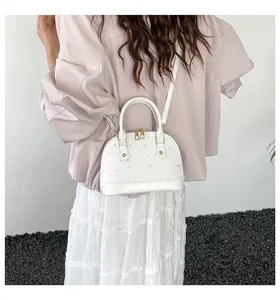 Vue détaillée du sac à main blanc avec motif d'étoiles, zips doubles et poignées.