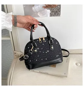 Vue détaillée du sac à main dôme noir avec imprimé d'étoiles et des accessoires dorés.