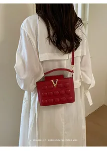 Chic borsa a tracolla rossa con chiusura V dorata, design alla moda per donne.