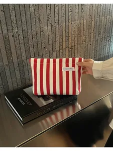 Gros plan d'une pochette en toile rayée rouge et blanche avec détail d'étiquette sur table.
