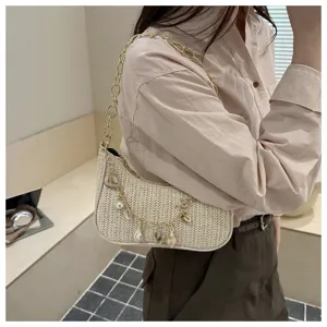 Woven straw underarm bag with chain and shell charms, stylish shoulder bag for summer beach.
