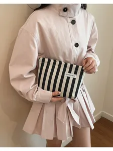Détail en gros plan de la pochette rayée noir et blanc tenue par le mannequin, tendance.