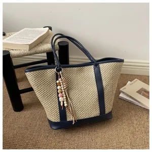 Vrouwen zomer stro geweven tote tas met marineblauwe pu lederen afwerking en kraal hanger charm.