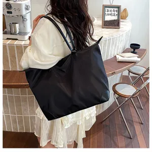 Detail view of large capacity black nylon travel tote bag with leather handles for daily use.