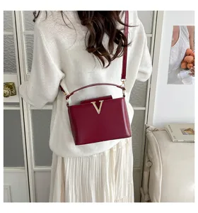 Élégant sac à bandoulière rouge en cuir avec logo V métallique, design chic pour femmes au quotidien.
