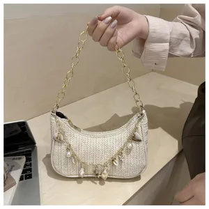 Woven straw underarm bag detail showing stylish gold chain handle and lovely shell pearl pendants.