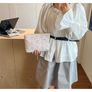 Pochette clutch rayée élégante pour femme avec joli motif de nœud rose et étiquette pratique.