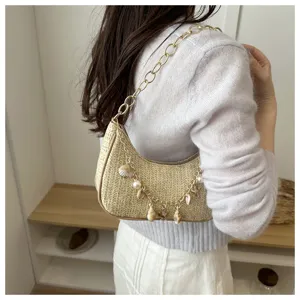 Woven straw underarm bag with gold chain and shell charms, stylish summer beach shoulder bag.