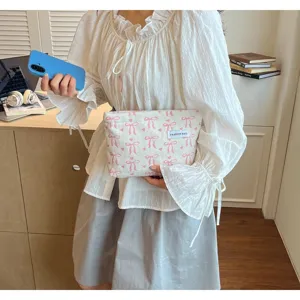 Détail de pochette rayée avec motif de nœuds roses et étiquette élégante.