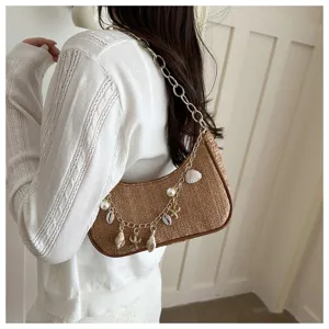 Woven straw shoulder bag for women, stylish summer beach handbag with chain and shell charms.