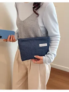 Vue détaillée de la pochette élégante en denim bleu foncé dotée d'une étiquette blanche.