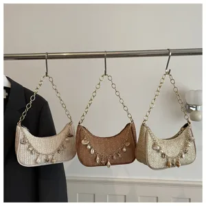 Woven straw underarm bag detail showcasing stylish chain strap and cute shell pearl charms.