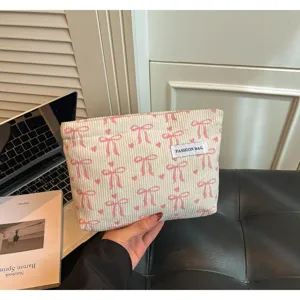 Vue détaillée de la trousse de toilette en velours côtelé avec nœuds, texture douce en gros plan.