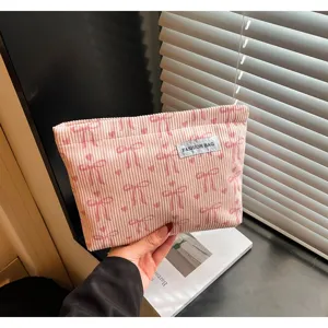 Détail de pochette cosmétique en velours côtelé rose avec joli motif de nœud et texture de tissu.