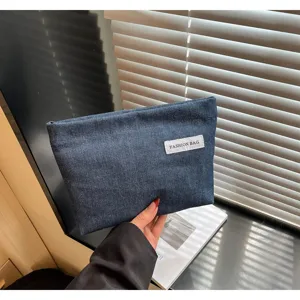 Vue détaillée de la pochette en jean, trousse cosmétique portable avec étiquette blanche.