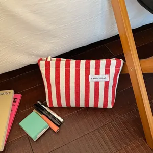 Sac de maquillage en toile rayée rouge et blanche trousse de toilette zippée élégante.