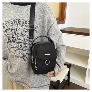 Vista di dettaglio della borsa a tracolla nera in nylon, dimensioni compatte e cerniere resistenti.