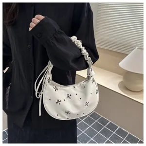 Primo piano di una borsa a tracolla bianca in stile coreano con fiocchi neri e pois carini.