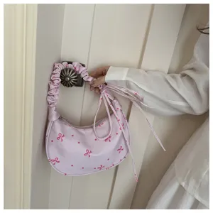 Dettaglio di una graziosa borsa a tracolla rosa con fiocco e pois sulla maniglia.