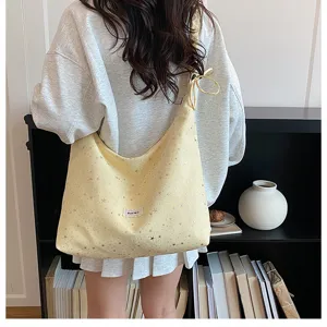 Detailed lifestyle shot of a yellow starry print canvas tote bag with shoulder strap.