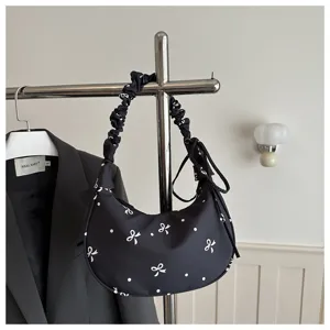 Borsa a spalla nera a mezzaluna con stampa fiocco bianco e pois e manico arricciato.