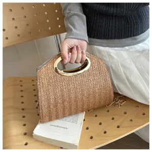 Primo piano della borsa di paglia chic con manico metallico rotondo e catena raffinata.
