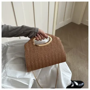 Vista dettagliata della elegante borsa in paglia con manico ad anello dorato.