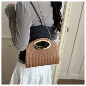 Primo piano della borsa in paglia intrecciata con elegante manico ovale dorato e catena.