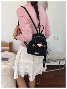Vue détaillée du mini sac à dos noir avec adorable patch de chien et bretelles au quotidien.