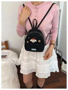 Vue détaillée d'un mini sac à dos noir avec patch de chien et boutons en bois porté.
